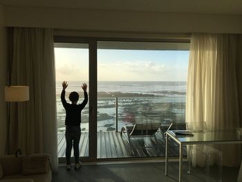 Rear view of boy looking through window