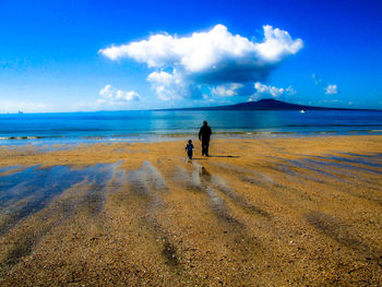 Rear view of people on beach against sky