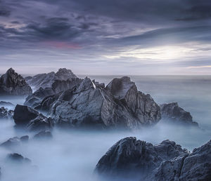 Scenic view of rocks in sea against sky during sunset