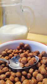 Close-up of breakfast cereals in bowl by milk
