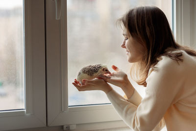 Girl holds cute hedgehog in her hands. portrait of pretty curious muzzle of animal. favorite pets. 