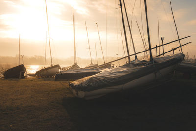 Sailboats moored in marina at sunset