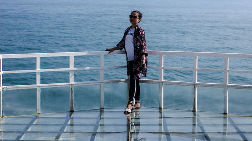 Man standing on railing against sea