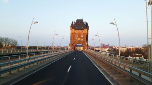 Empty road against built structure and clear sky