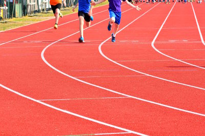 Rear view of athletes running on sports track