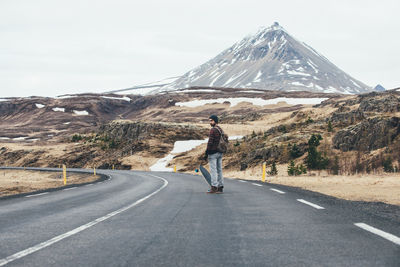 Man standing with skateboard on highway