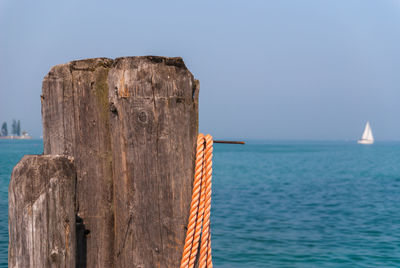 Wooden posts in sea against clear sky