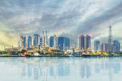 Sea by modern buildings against sky in city