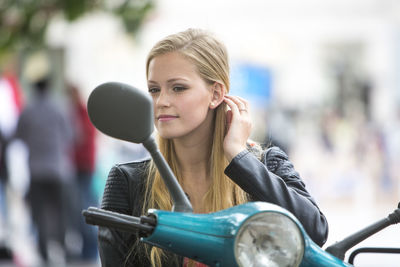 Young woman looking in side-view mirror of motor scooter