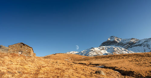 Low angle view of snowcapped mountains against clear blue sky