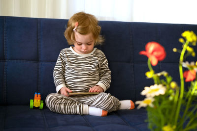 Cute caucasian blonde baby girl,toddler, infant, adorable kid 1,2 years on sofa using mobile phone