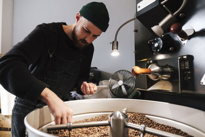 Coffee roaster examining coffee beans at factory