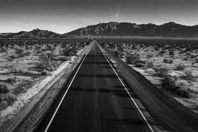 Road leading towards mountain range against sky