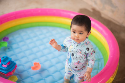 High angle view of baby girl standing in wading pool