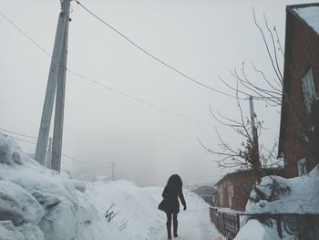 Man walking on snow covered landscape against sky