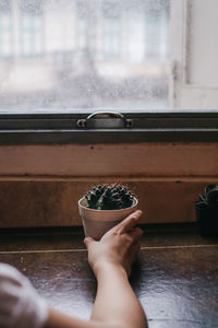 Midsection of person holding glass window at home