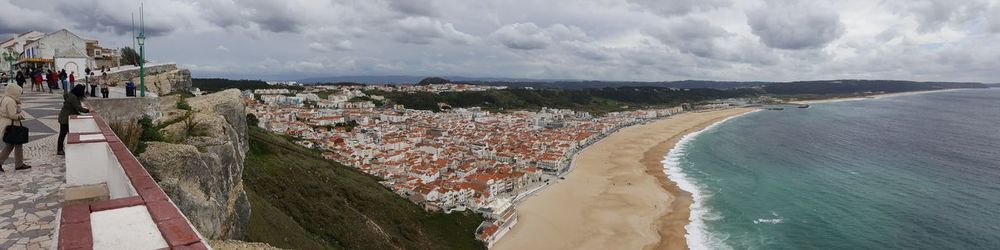 Panoramic view of people at beach against sky