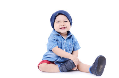 Cute boy sitting against white background