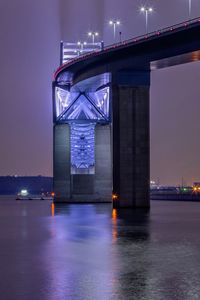 Illuminated bridge over river at night