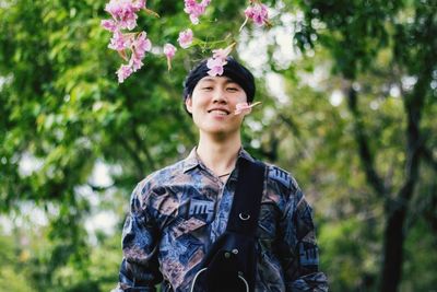 Portrait of smiling young man standing against trees