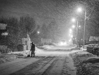 Man walking on snow covered road at night