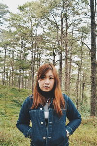 Portrait of young woman standing against in forest