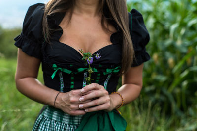 Midsection of young woman holding flower