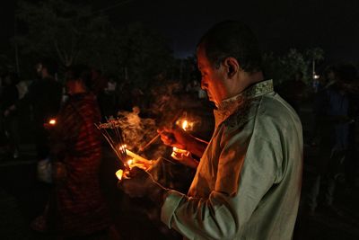 Man holding dia, oil-lamp at rakher upobash barodi lokhnath brahmachari ashram in night time 