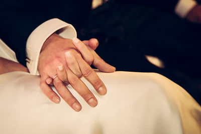 Midsection of newly wed couple holding hands