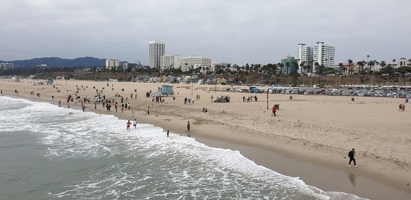 People on beach against sky in city