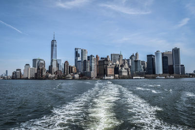 Sea and buildings in city against sky