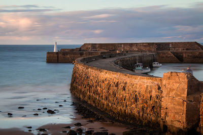 Boats in sea against cloudy sky