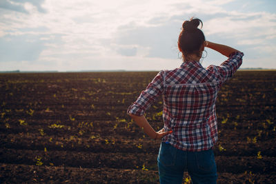 Rear view of woman standing on field against sky