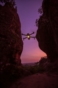 Rock formation amidst trees against sky at sunset