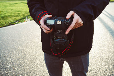 Midsection of man photographing on road