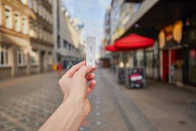 Midsection of person holding umbrella on street in city