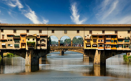 Arch bridge over river in city against sky