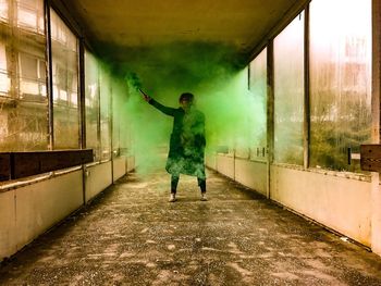 Woman with green smoke grenade in abandoned building