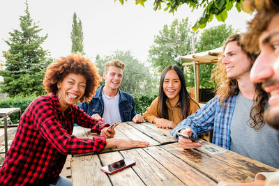 Portrait of smiling friends standing against trees