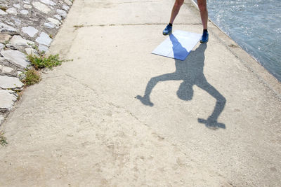 Low section of man standing in front of mat on promenade