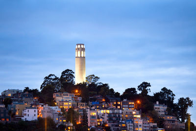 Illuminated buildings in city against sky at dusk