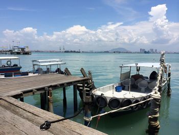 Boats moored at harbor against sky