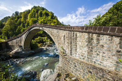 Arch bridge over river against sky