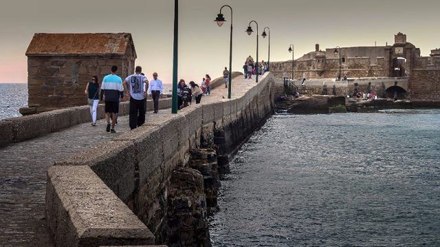 water, sea, built structure, architecture, building exterior, men, lifestyles, leisure activity, clear sky, person, waterfront, incidental people, sky, nautical vessel, day, travel, large group of people, tourist, transportation