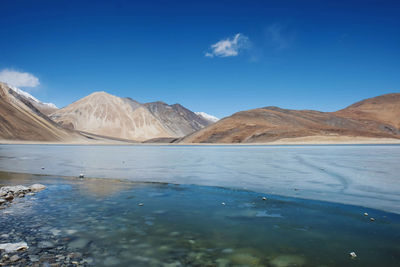 Scenic view of lake and mountains against blue sky