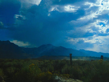 Country road leading towards mountains against blue sky