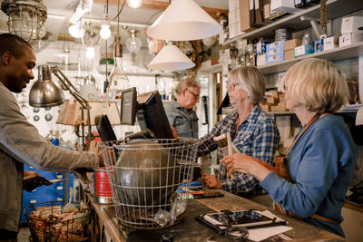 Male customer standing with female owners at checkout in hardware store