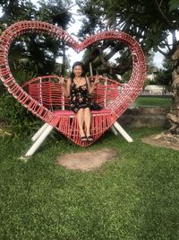 Portrait of happy girl sitting on grass against trees