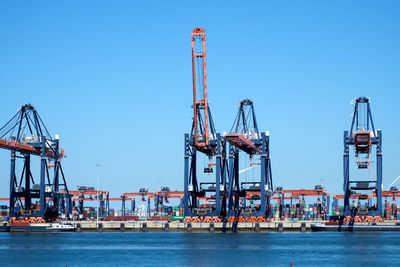 Cranes at commercial dock against clear sky