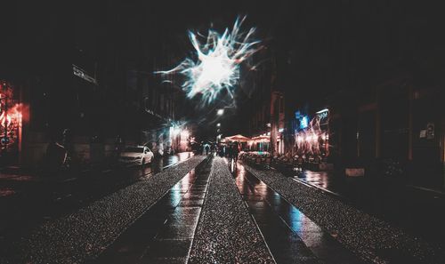 Firework display over city street at night